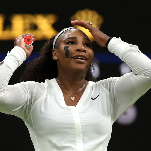 Serena Williams bei einem Tennisspiel, mit einem Pflaster auf der Wange und einem Ball in der Hand.