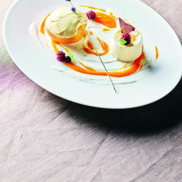 Ein Teller mit zwei Desserts, garniert mit Beeren, Lavendel und Karamellsauce.