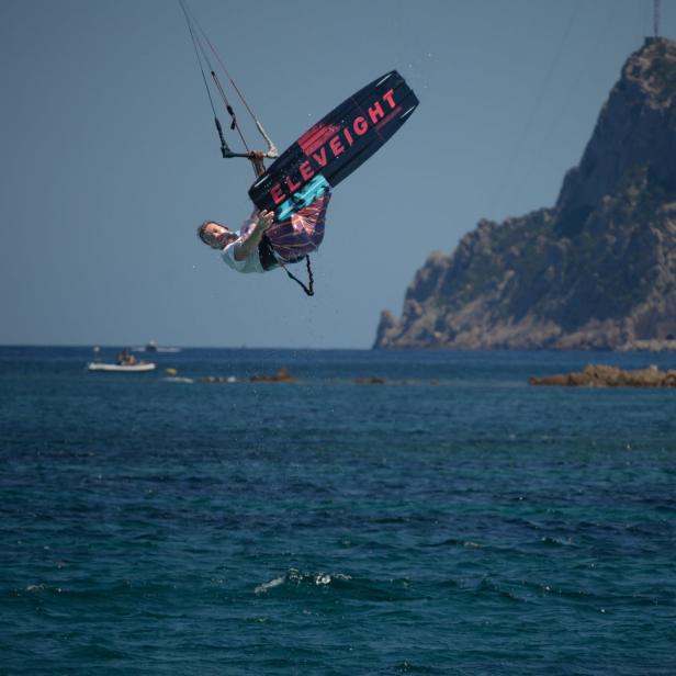 Ein Kitesurfer macht einen Trick in der Luft über dem Meer.