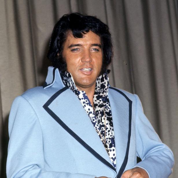 Elvis Presley in einem hellblauen Anzug mit einem auffälligen Hemd.
