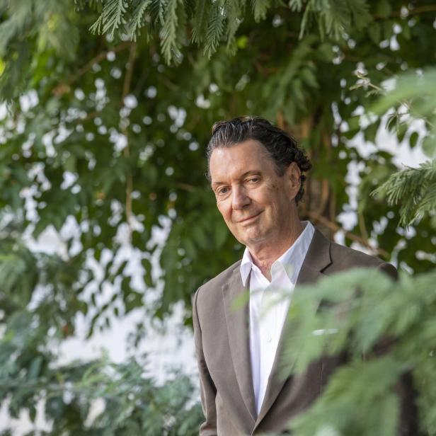 Ein Mann in einem Anzug steht vor einem Baum.