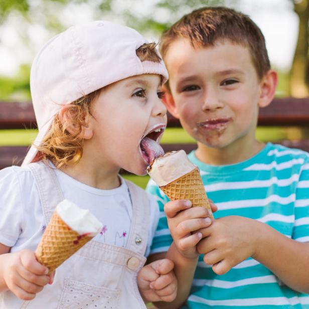 Zwei Kinder essen Eiswaffeln im Freien.