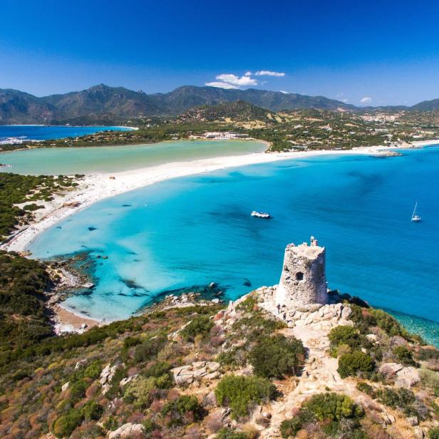 Ein Blick auf den Strand von Chia mit einem alten Turm im Vordergrund.