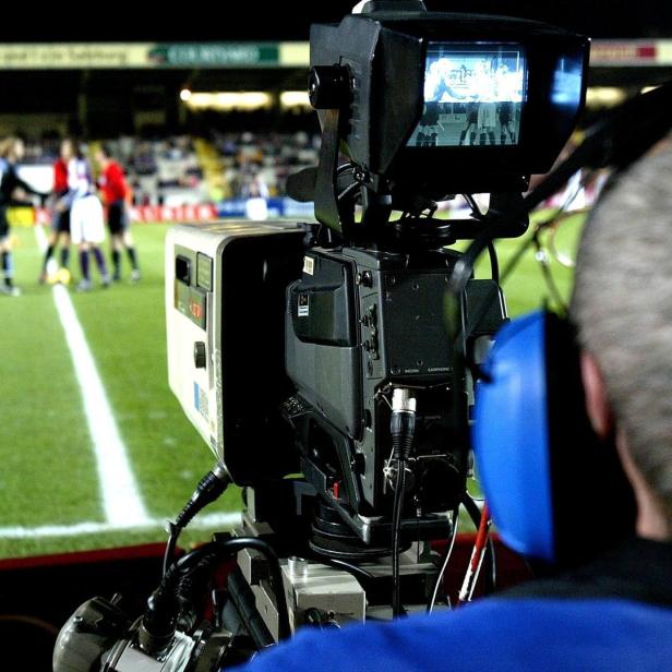 Ein Kameramann filmt ein Fußballspiel im Stadion.