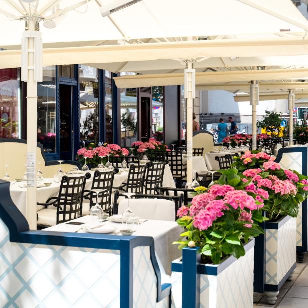 Einladende Außenterrasse eines Restaurants mit blühenden Hortensien und gedeckten Tischen.