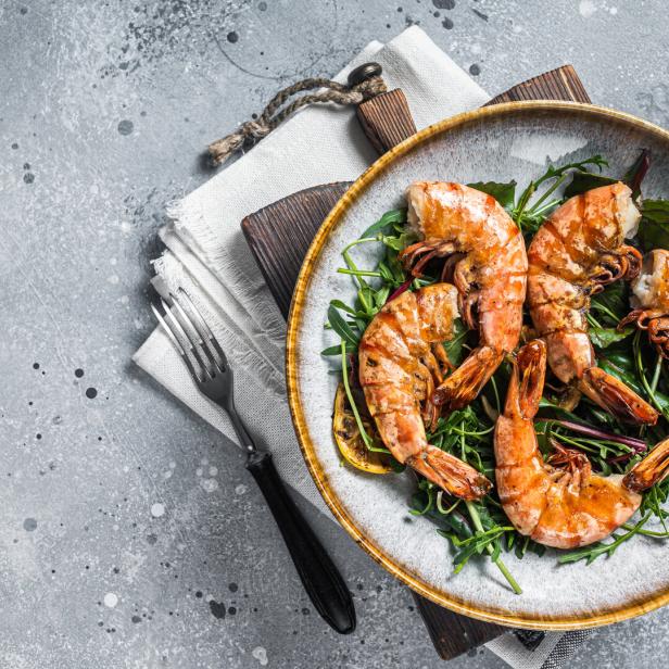 Salad with grilled Giant shrimps prawns in plate. Gray background. Top view. Free copy space