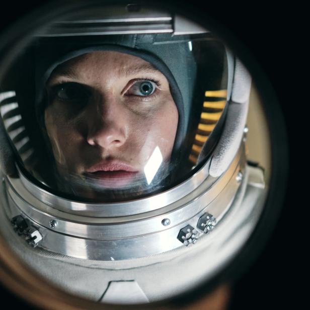 Eine Astronautin blickt durch das Visier ihres Helms.
