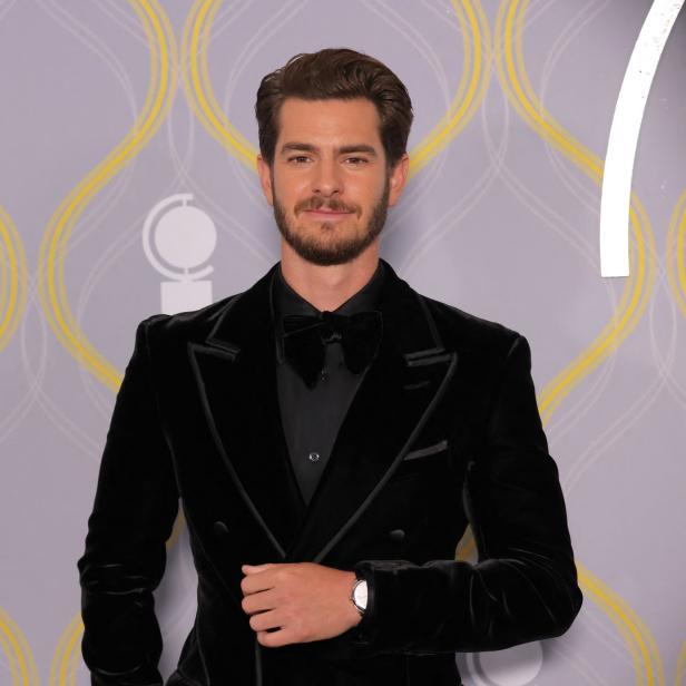 Andrew Garfield in einem schwarzen Samtanzug vor einem gemusterten Hintergrund.