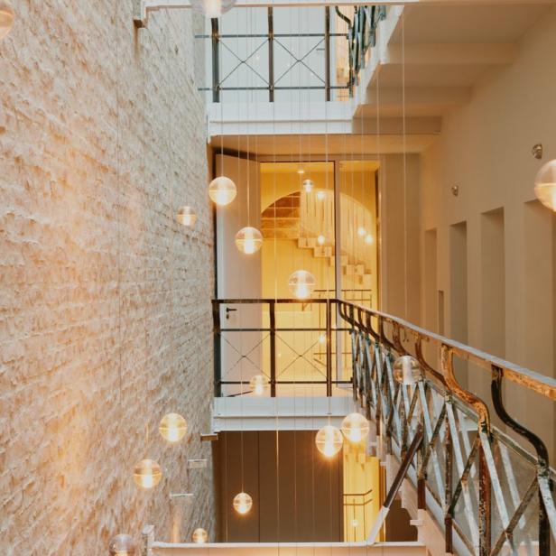 Ein Treppenhaus mit mehreren Etagen und kugelförmigen Lampen, die von der Decke hängen.