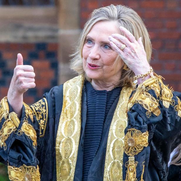 Hillary Clinton in akademischer Kleidung gibt einen Daumen nach oben.