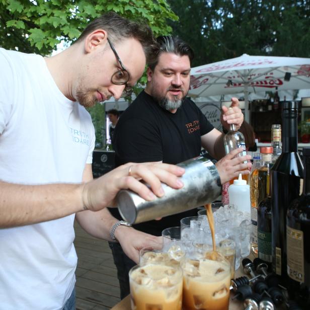 Zwei Barkeeper mixen Cocktails an einer Bar im Freien.