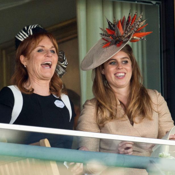 Sarah Ferguson und Prinzessin Beatrice tragen Hüte und lächeln auf einem Balkon.