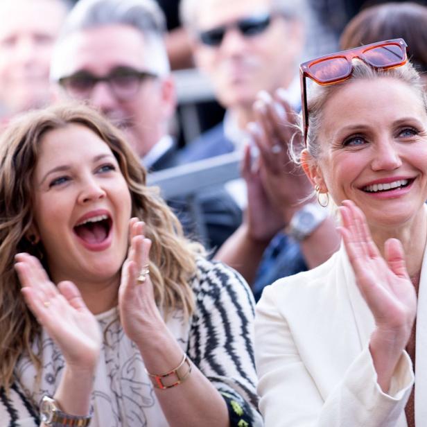 Drew Barrymore und Cameron Diaz klatschen bei einer Veranstaltung.