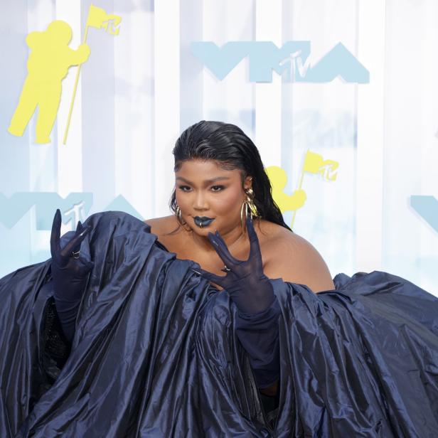 Lizzo posiert in einem voluminösen, dunkelblauen Kleid auf dem roten Teppich der VMAs.
