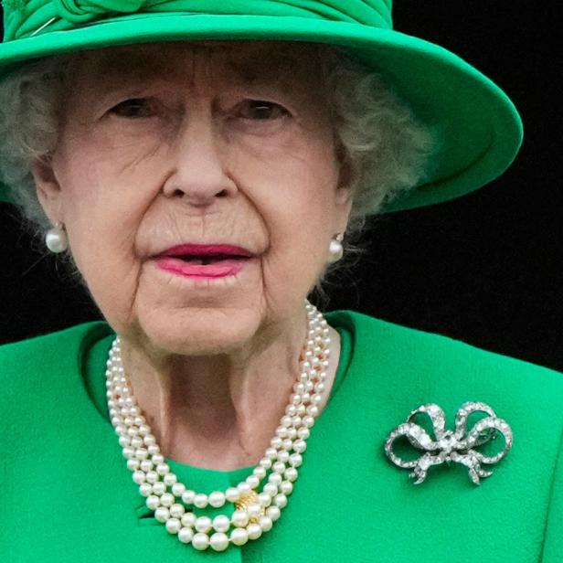 Königin Elisabeth II. trägt einen grünen Hut und eine dreireihige Perlenkette.