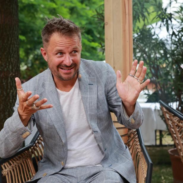 Ein Mann in einem karierten Anzug gestikuliert im Freien.