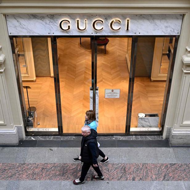 Zwei Personen gehen an einem Gucci-Geschäft vorbei.