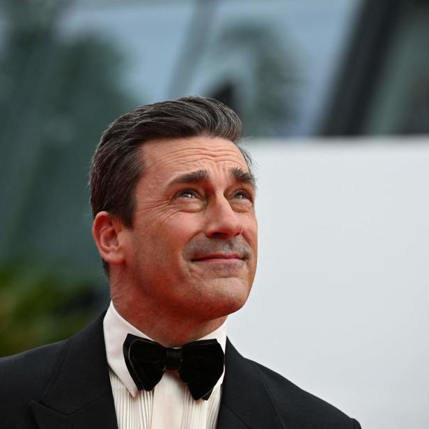 Jon Hamm in einem schwarzen Smoking mit Fliege blickt nach oben.