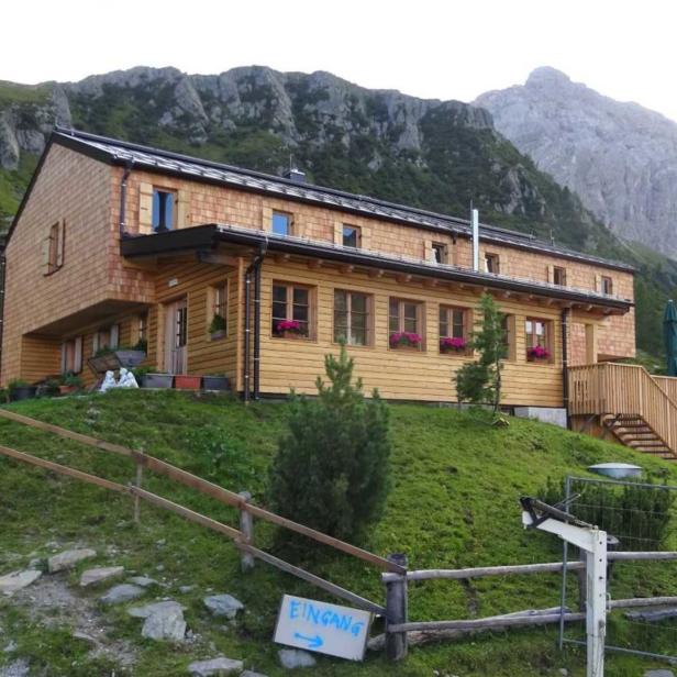 Ein hölzernes Berghaus liegt vor einer Bergkulisse.