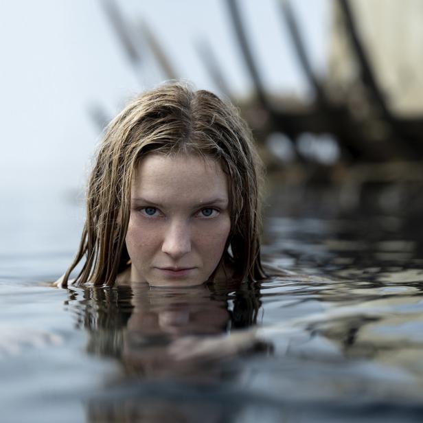 Eine Frau mit blonden Haaren taucht aus dem Wasser auf.