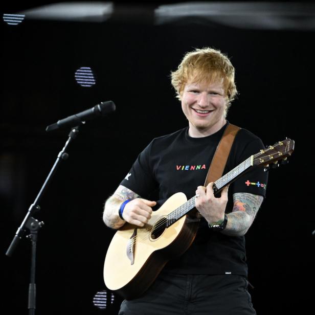 Ed Sheeran tritt mit seiner Gitarre auf einer Bühne auf.