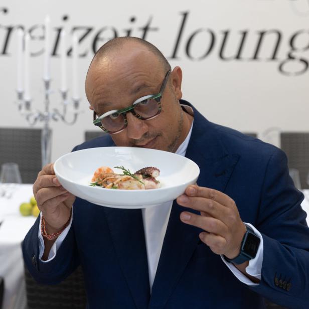 Ein Mann mit Brille betrachtet ein Gericht mit Meeresfrüchten in einem Restaurant.