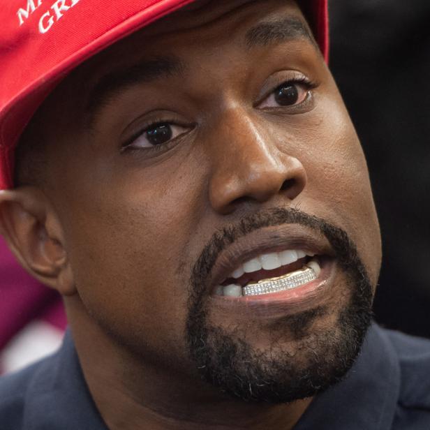 Nahaufnahme von Kanye West mit einem roten „Make America Great Again“-Hut und Grillz.