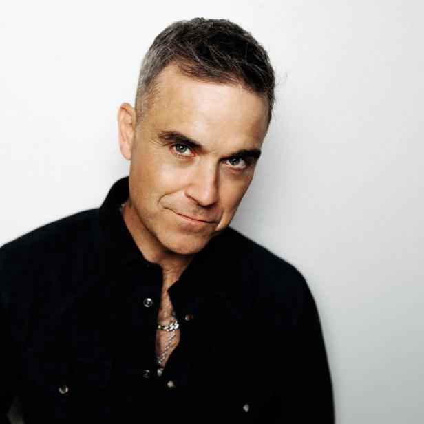 Porträt von Robbie Williams vor einem weißen Hintergrund.
