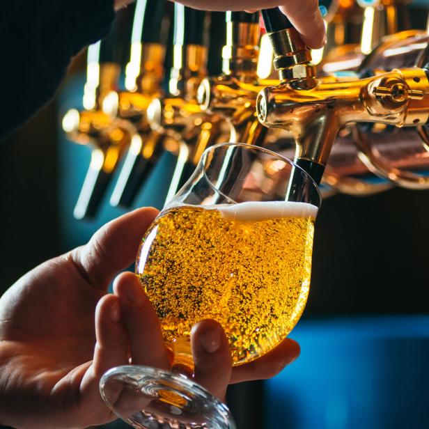 Ein Mann zapft ein Glas Bier an einer goldenen Zapfanlage.