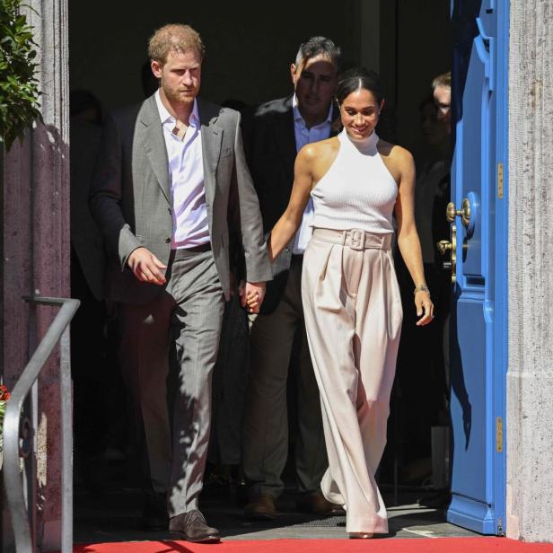 Prinz Harry und Meghan Markle verlassen händchenhaltend ein Gebäude.