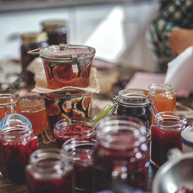 Verschiedene Gläser mit selbstgemachter Marmelade und eingelegten Feigen auf einem Holztisch.