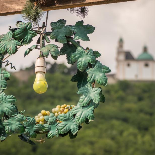 Ein dekorativer Weinkranz mit Glühbirne vor einer Kirche auf einem Hügel.