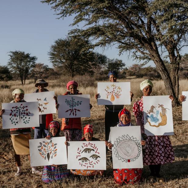 Eine Gruppe afrikanischer Frauen präsentiert ihre Zeichnungen in der Natur.