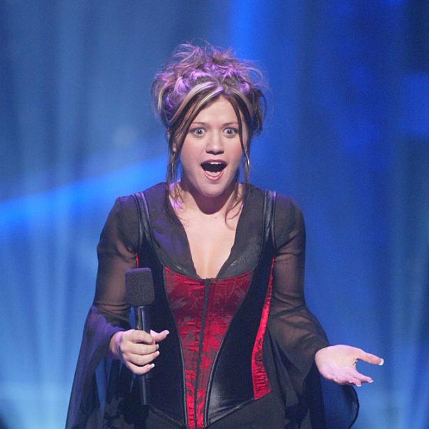 Kelly Clarkson steht mit offenem Mund und Mikrofon auf einer Bühne.