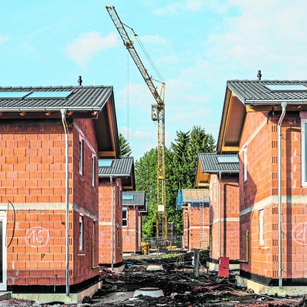 Im Bau befindliche Reihenhäuser aus roten Ziegeln mit einem Baukran im Hintergrund.