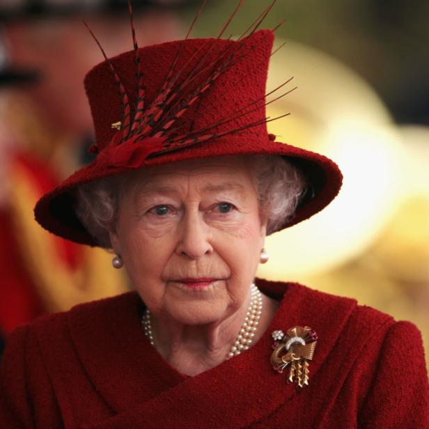 Königin Elisabeth II. mit einem roten Hut und passendem Kostüm.