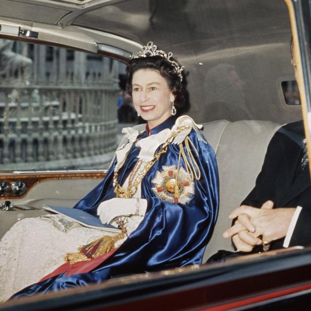 Königin Elisabeth II. mit Tiara und blauem Umhang in einer Limousine.