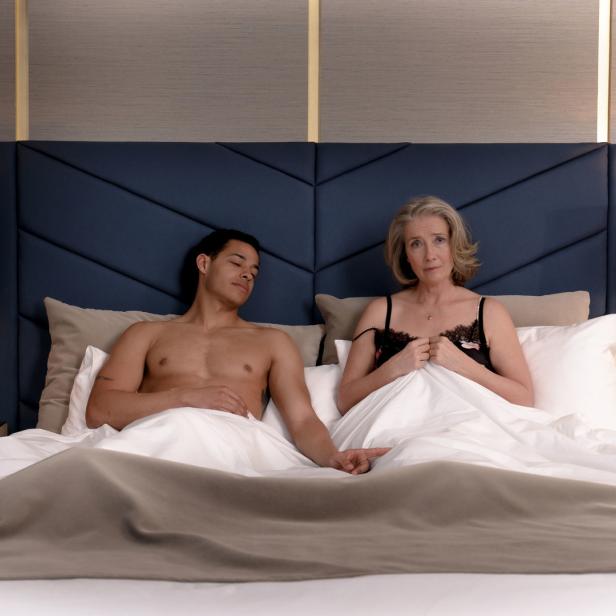 Eine Frau und ein schlafender Mann liegen gemeinsam in einem Bett.