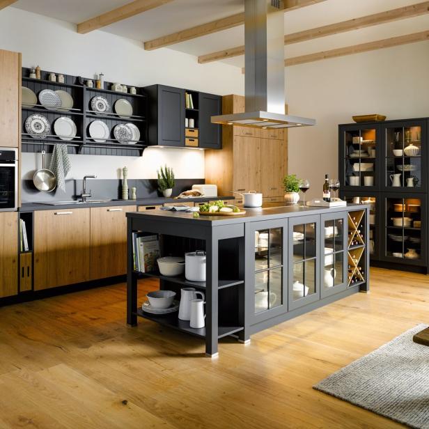 Eine moderne Küche mit Kochinsel, Holzboden und sichtbaren Holzbalken an der Decke.