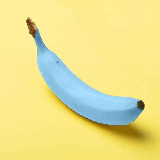 Eine hellblaue Banane liegt auf einem gelben Hintergrund.
