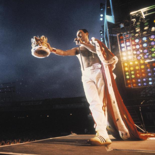 Freddie Mercury mit Krone und Umhang auf der Bühne.