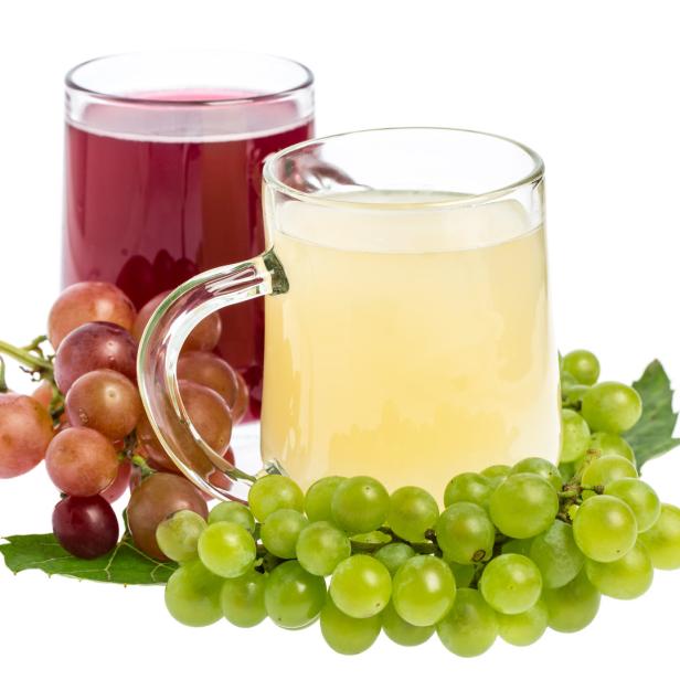 Zwei Gläser mit Traubensaft, umgeben von roten und grünen Trauben.