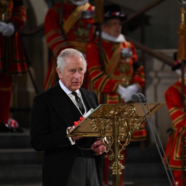 König Charles III. hält eine Rede vor Leibwächtern in traditioneller Kleidung.