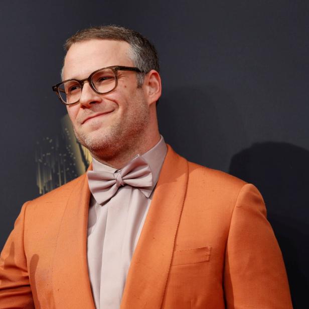 Seth Rogen in einem orangefarbenen Anzug mit Fliege gestikuliert.