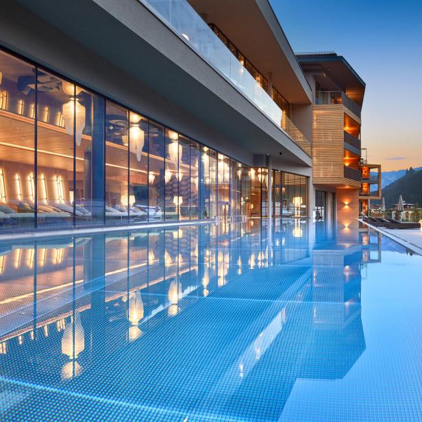 Ein Außenpool spiegelt die Architektur eines modernen Hotels in den Bergen wider.