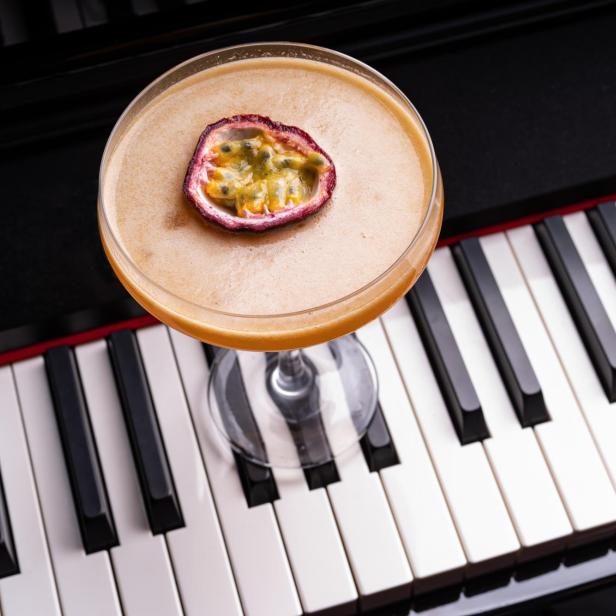 Ein Cocktail mit Passionsfruchtgarnitur steht auf einem Klavier.