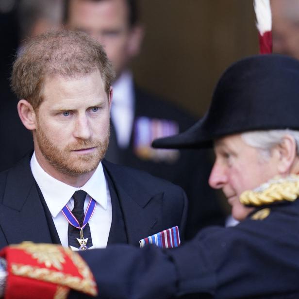 Prinz Harry im Gespräch mit einem Mann in Uniform und Dreispitz.