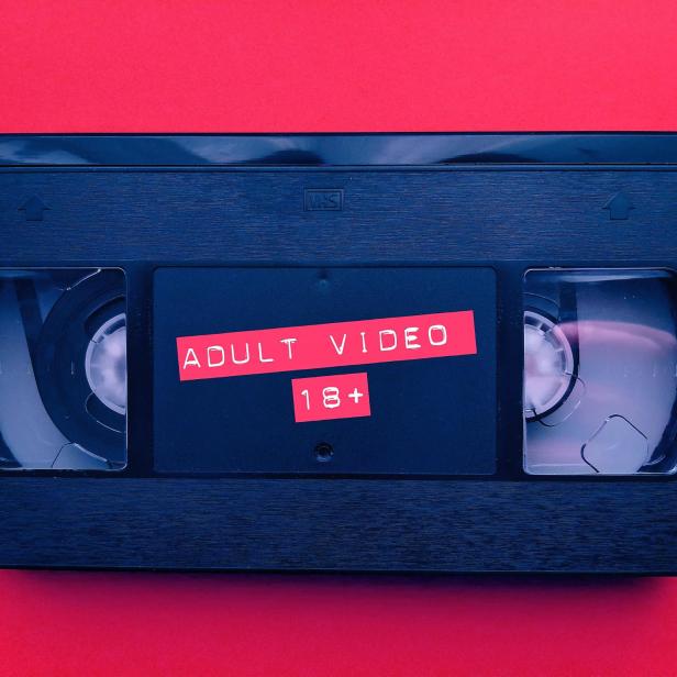 Eine VHS-Kassette mit dem Aufdruck „Adult Video 18+“ vor rotem Hintergrund.
