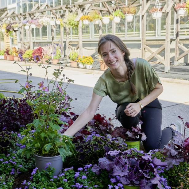 Eine Frau kniet in einem Garten und pflanzt Blumen.