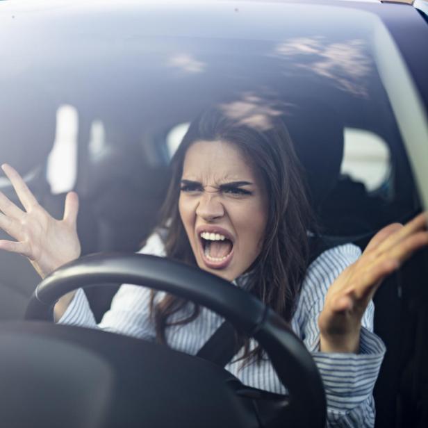 Eine wütende Frau gestikuliert im Auto während eines Staus.